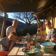 De Vos, buiten eten aan de picknicktafel, familie van Eelke met twee kindjes en drie volwassenen in de zon lachend